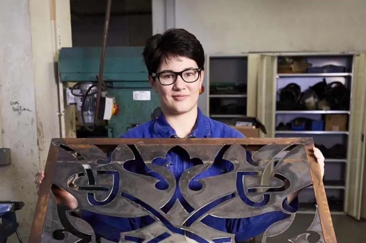Une jeune fille montre une plaque en fer forg&eacute;