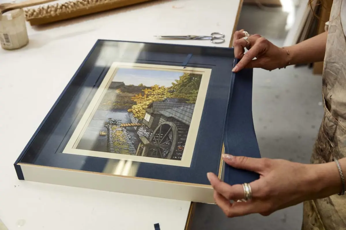 Deux mains tenant un cadre avec une photo &agrave; l'int&eacute;rieur