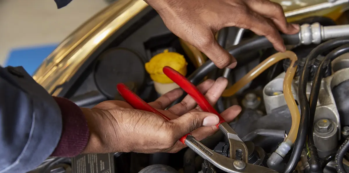 Gros plan sur les mains de Lukau tenant une pince dans un moteur