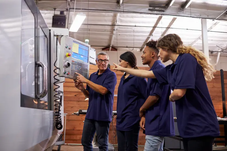 Un professeur montre une machine &agrave; 2 jeunes filles et 1 jeune homme