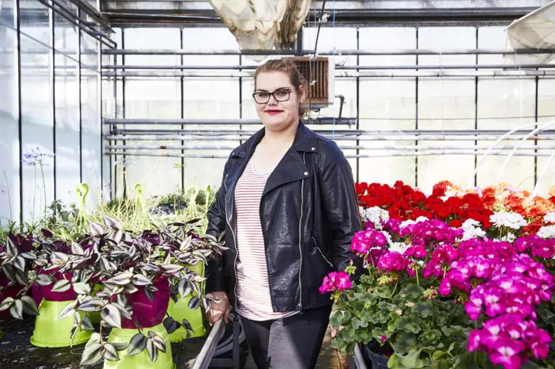 Jeune fille posant devant des pots de fleurs dans une serre
